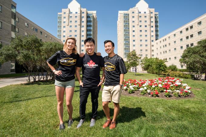 Three students posing for the camera on the academic green