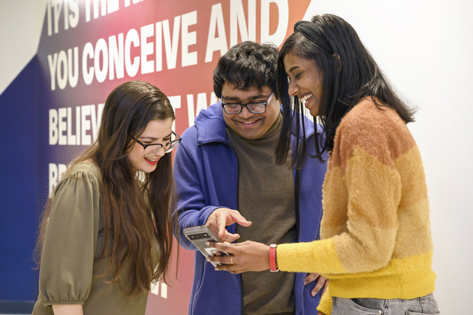 three people looking at the phone