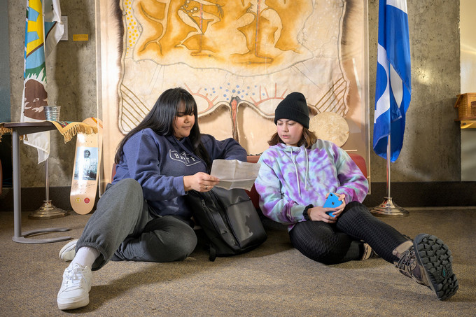 two students in a room looking at a paper