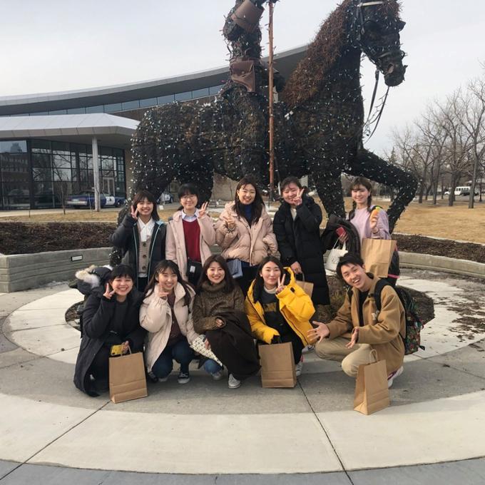 Students sitting under statue