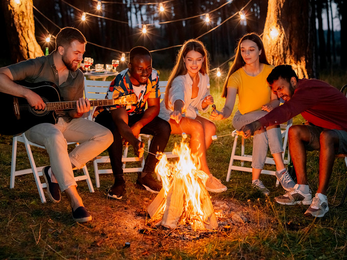 Young adults at a campfire playing guitar