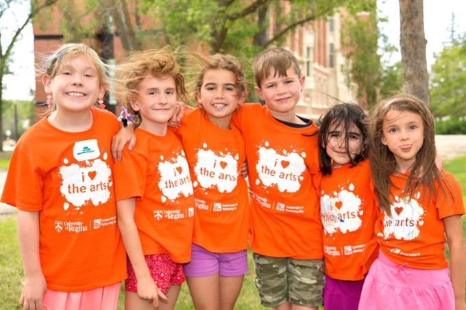 Group of summer campers smiling in orange t-shirts.