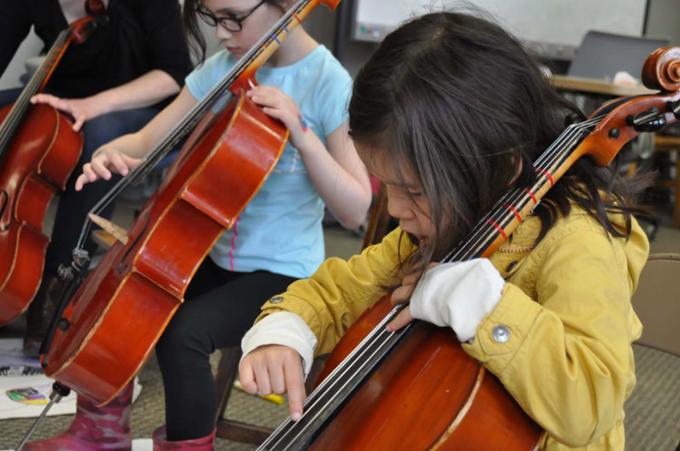 Group of children learning to play the cello.
