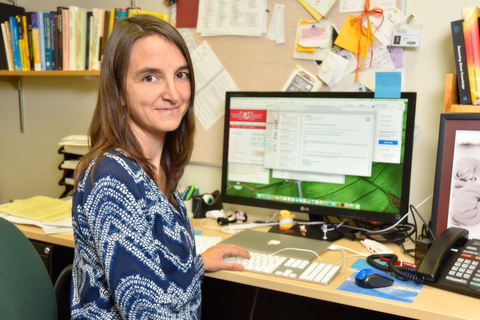 Student seated at desk looking at computer monitor.