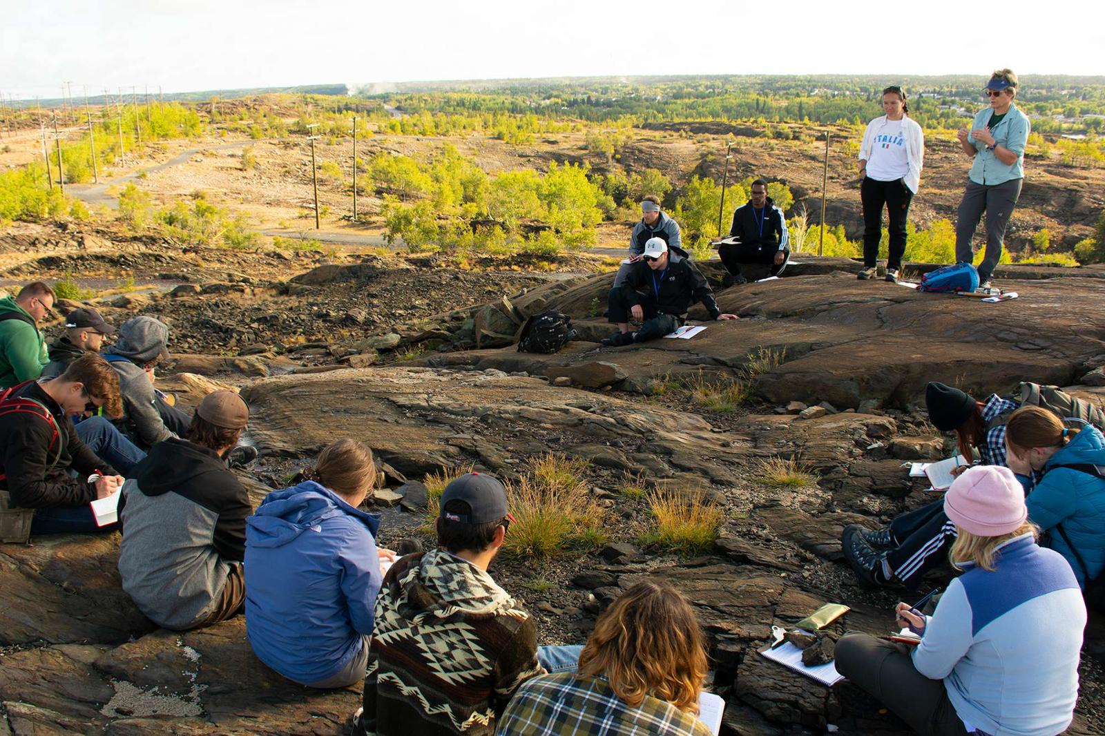 Students on a dig site listening to a professor