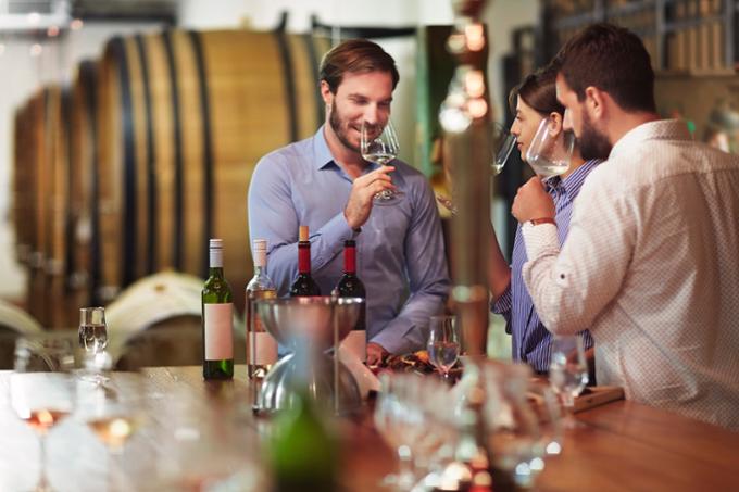 Group of adults smelling wine in their glasses. 
