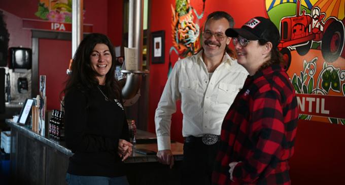 Three team members of Rebellion Brewing Co. standing together smiling. 