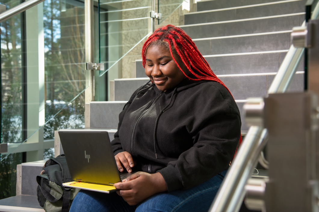 Student sitting on stairs on laptop