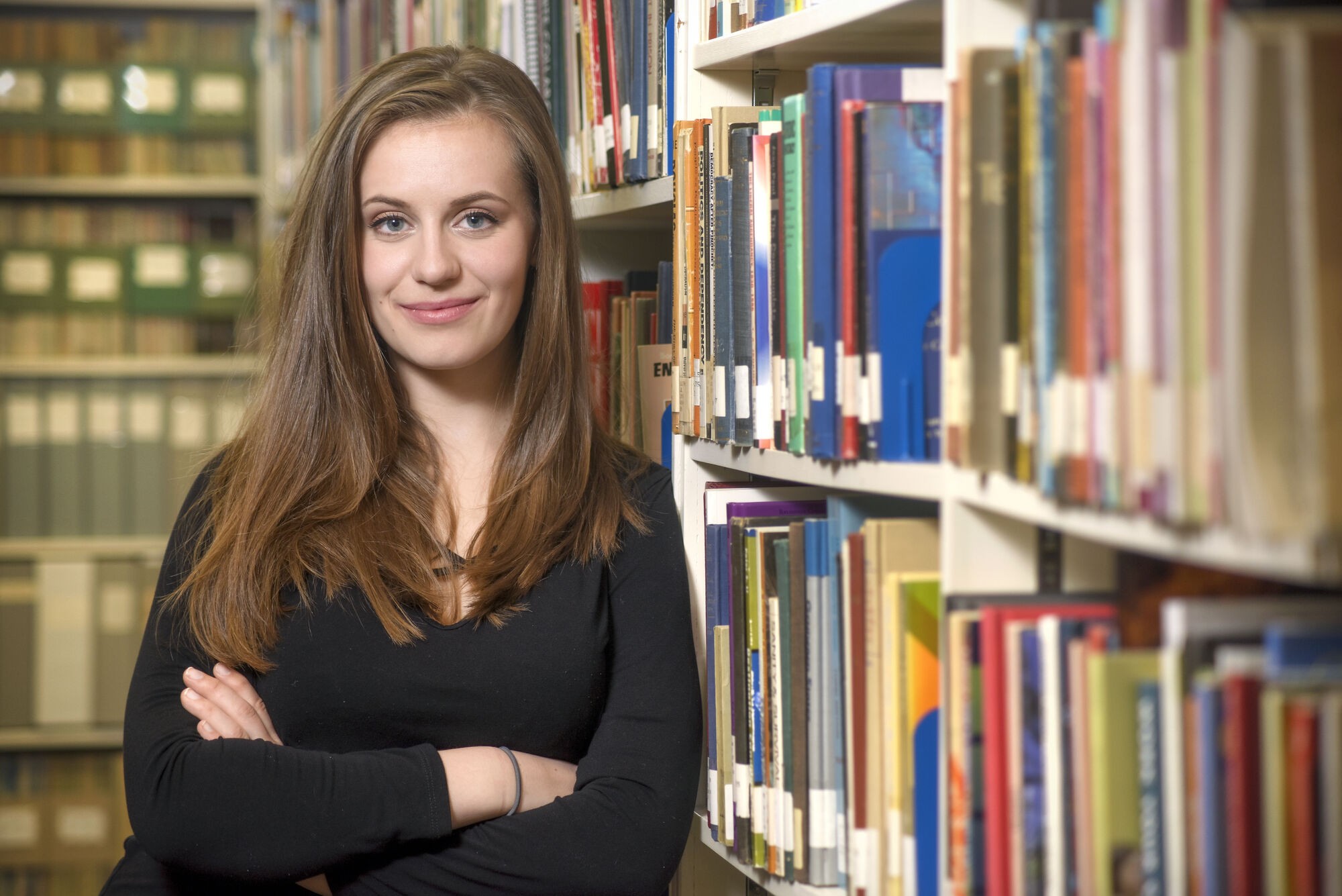 student smiles w bookshelf