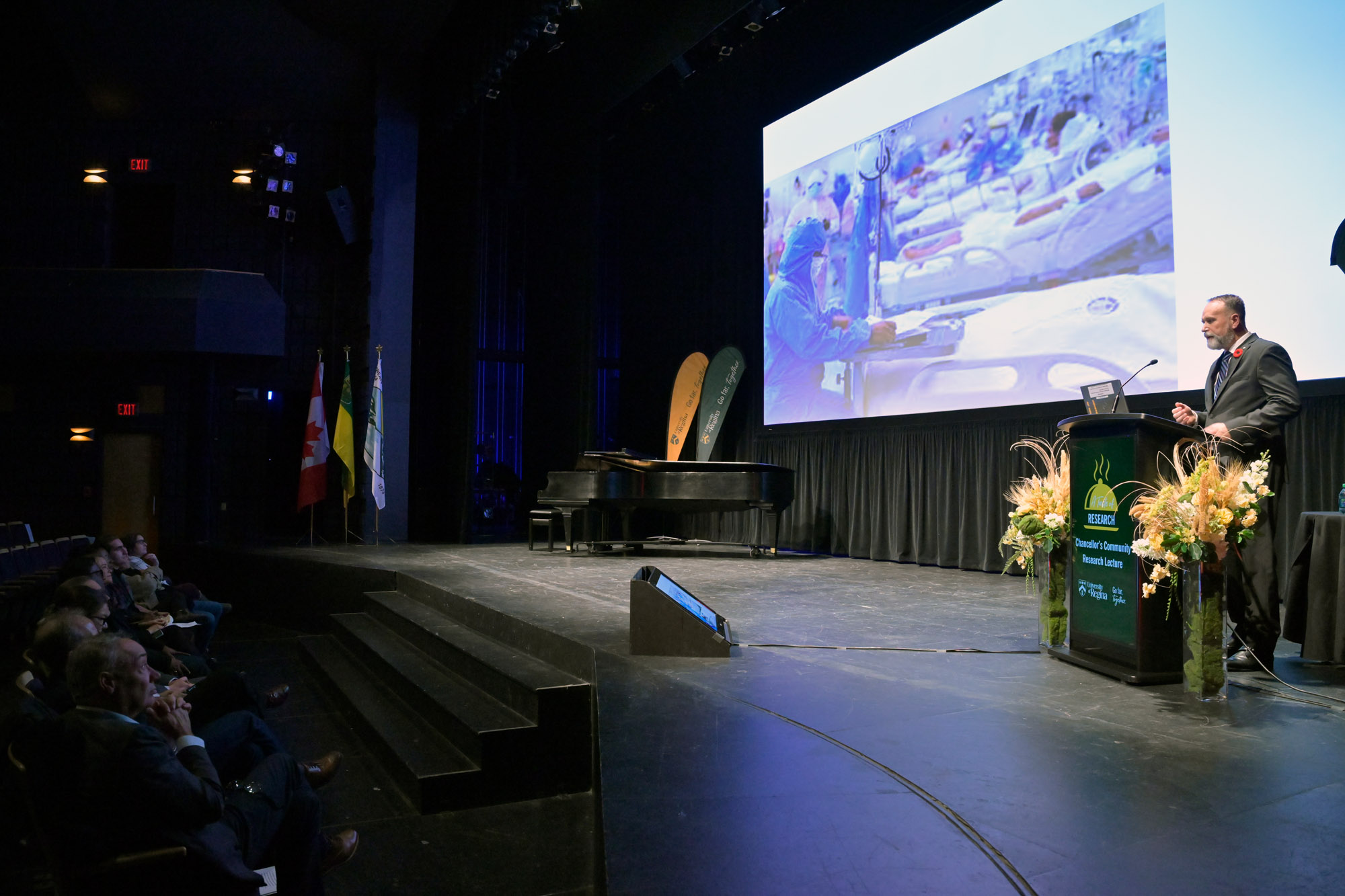 Extra wide shot of stage with podium and screen with presentation material. 