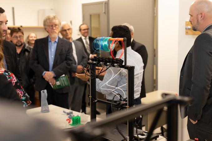 Group of people listen to researcher explain 3D printing