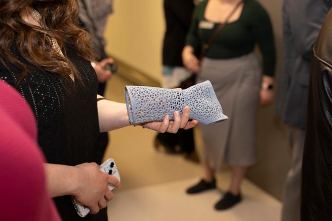 woman holds grey arm cast made by 3D printer