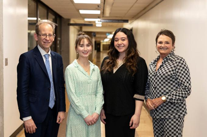 Four people standing in hallway smiling at camera