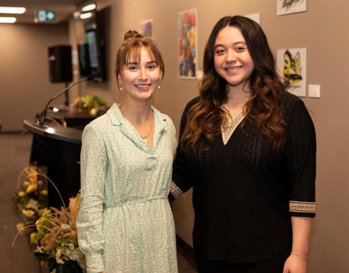 Two women stand together smiling