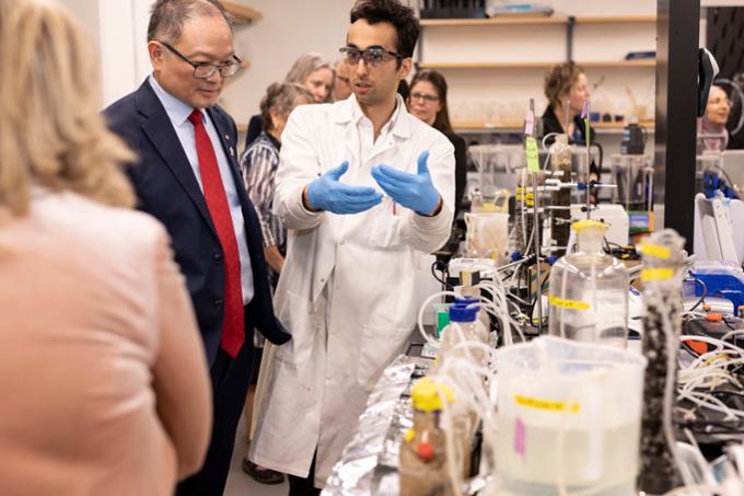 Student describes research in lab to man standing next to him