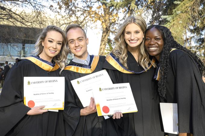 Students in gowns pose outside