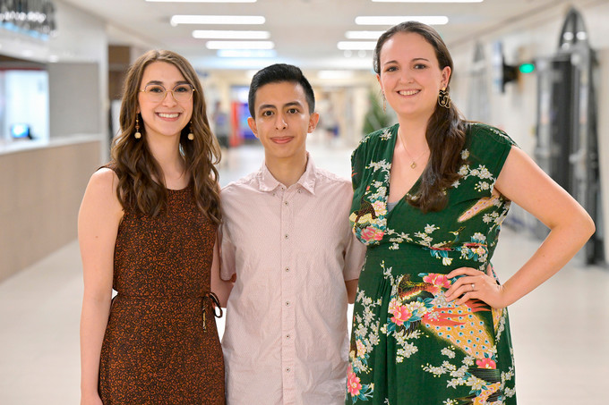 Three people stand in hallway.