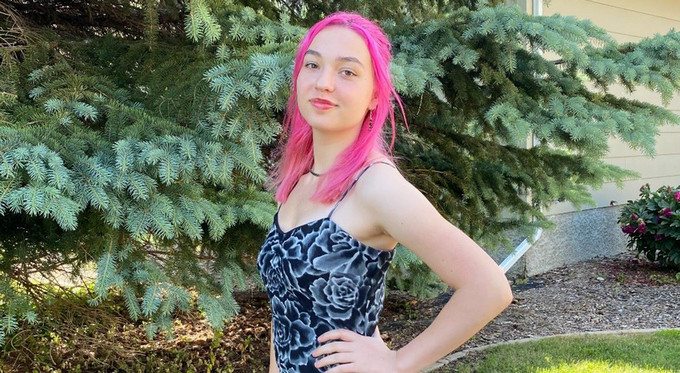 Woman poses outside infront of spruce trees.