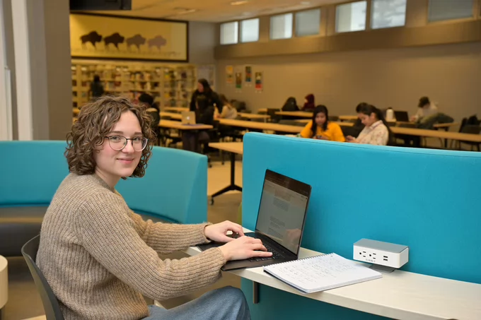 Woman sits working on a laptop.