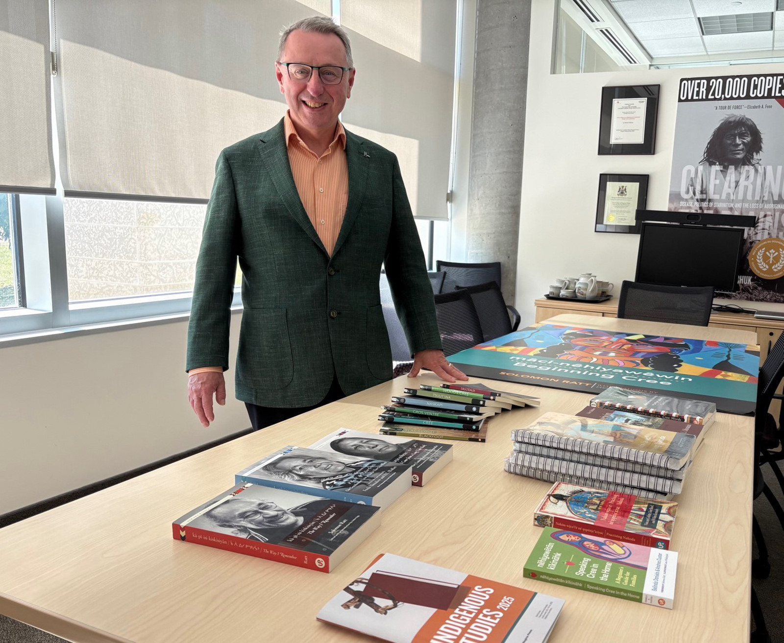 Man stands next to table with display of books.