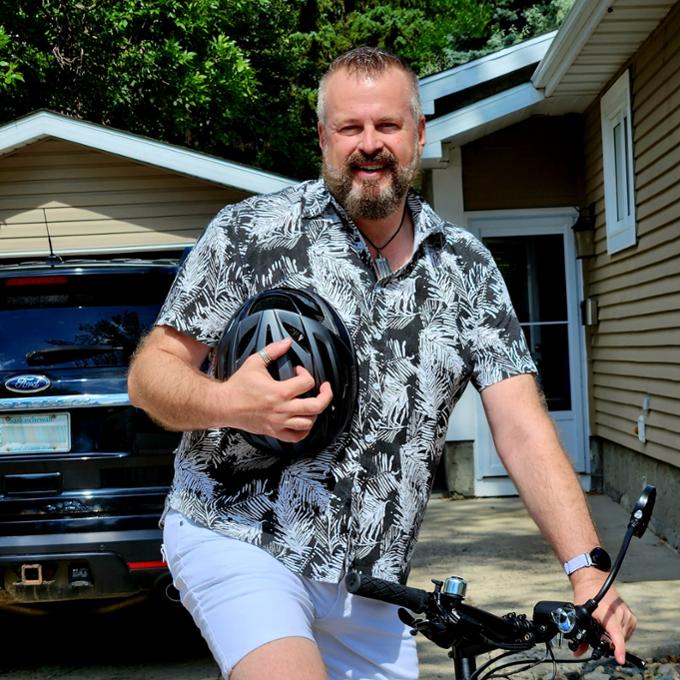 Thom Boivin, donor and U of R employee, smiles at the camera while holding his bicycle helmet.