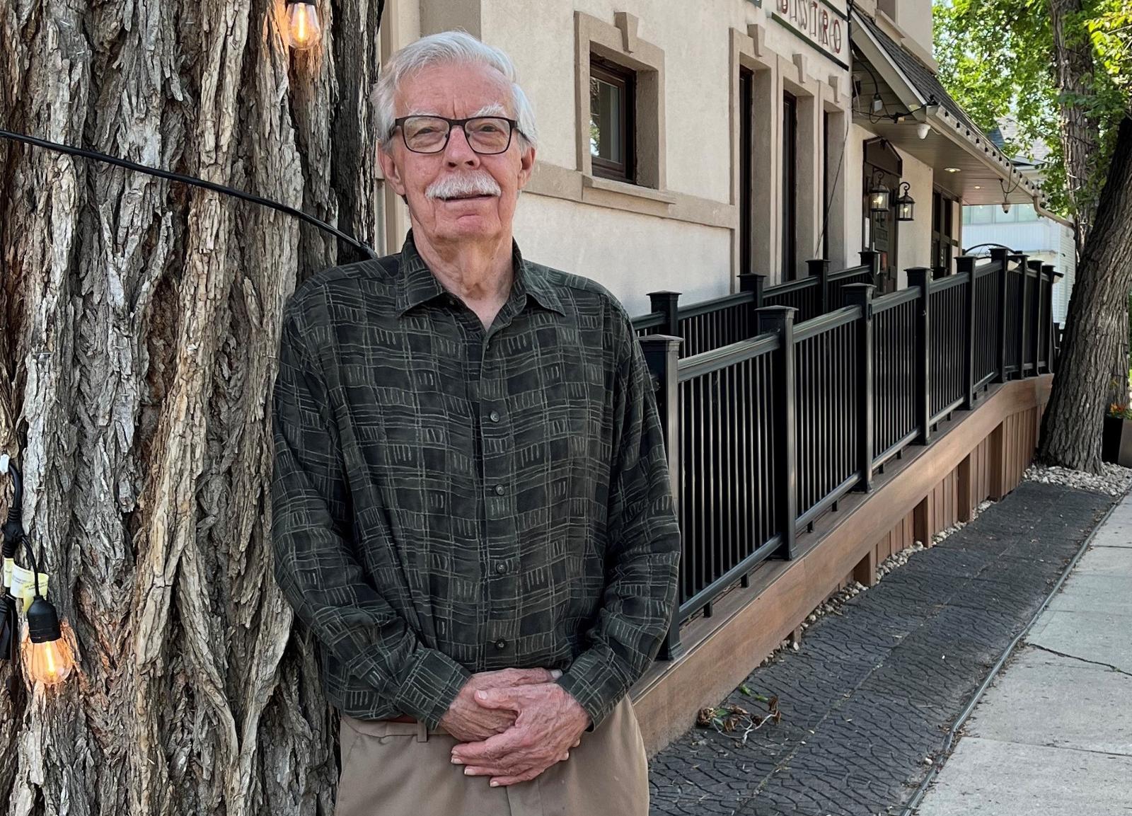 Man stands outside in front of building.