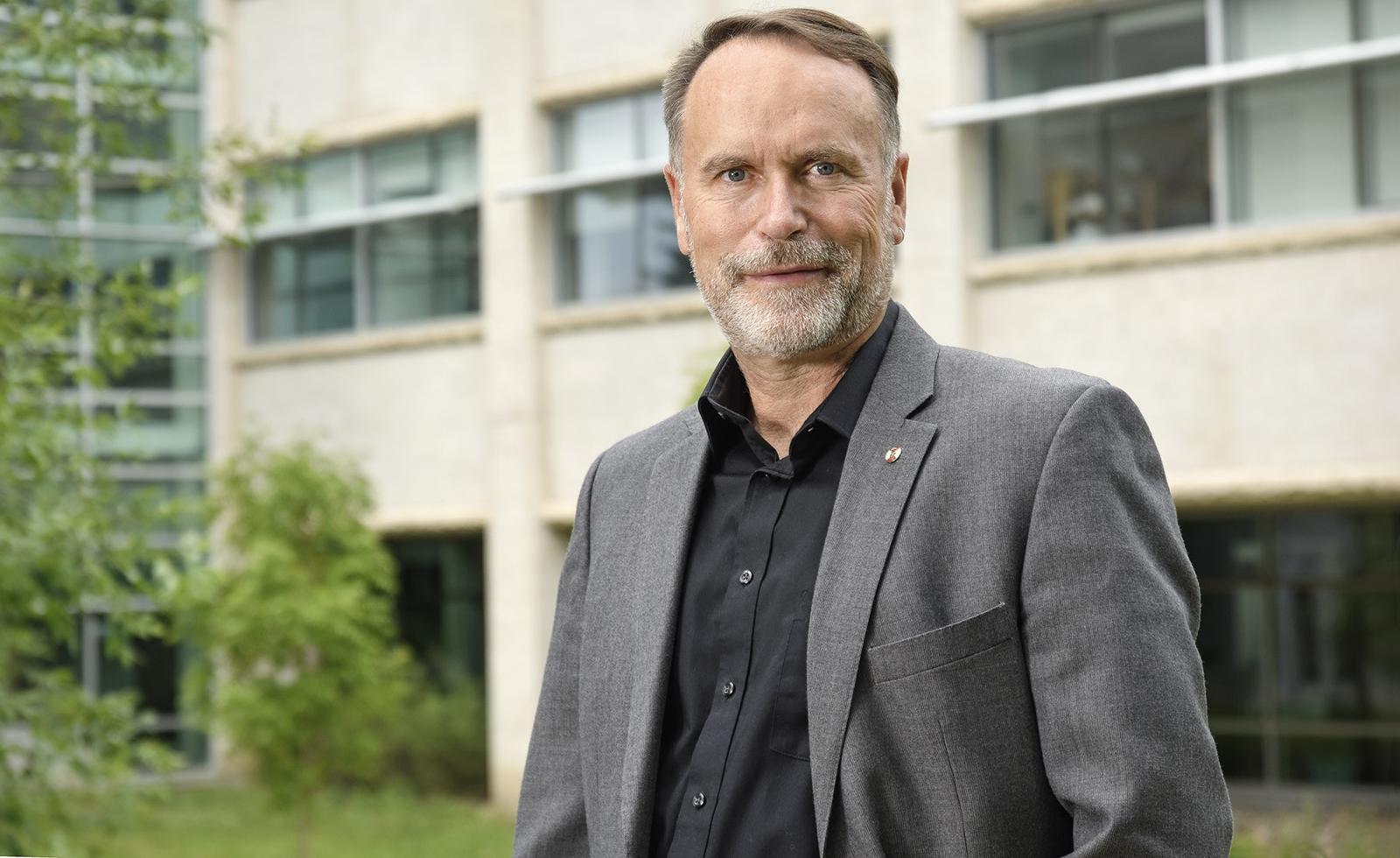 Man stands outside in front of building looking at the camera