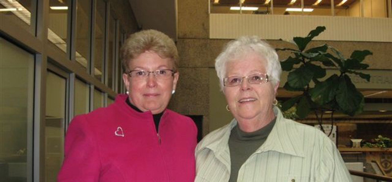 Two women stand smiling facing camera