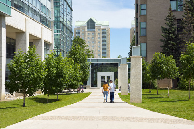 Two people walk outside toward building.