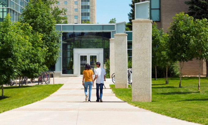 Two people walking towards a building.