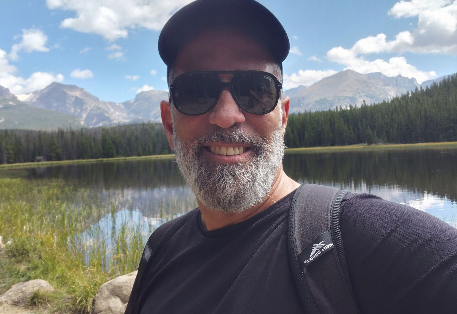 Man stands outside in front of mountains.
