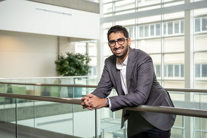 Man in suit smiles leaning on railing.