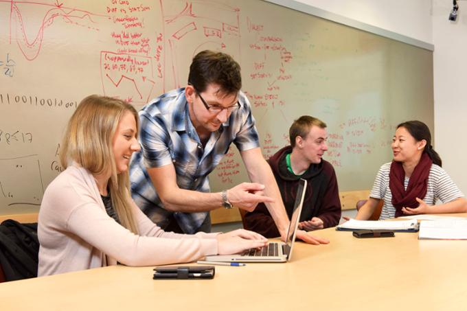 Dr. Oriet leans over a student's work