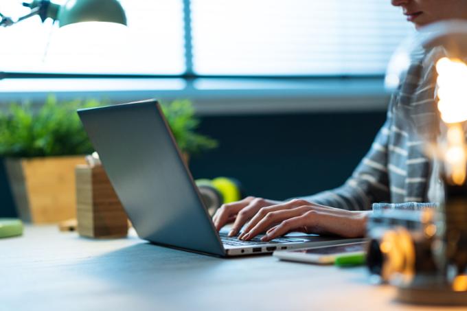 A set of hands typing on a laptop computer.