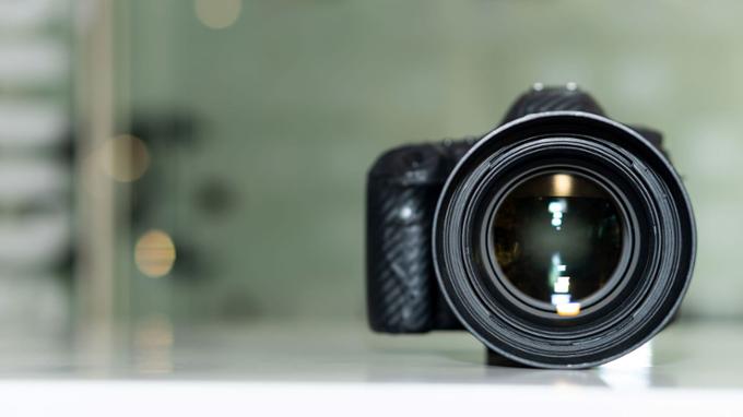 Black camera with the lens facing forwards on a green background