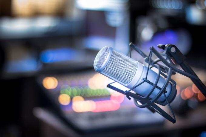 A microphone is in the foreground of a radio/podcast studio