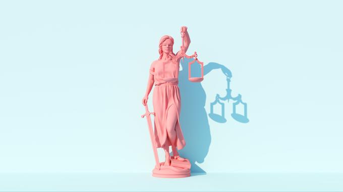A pink lady justice holds a set of scales