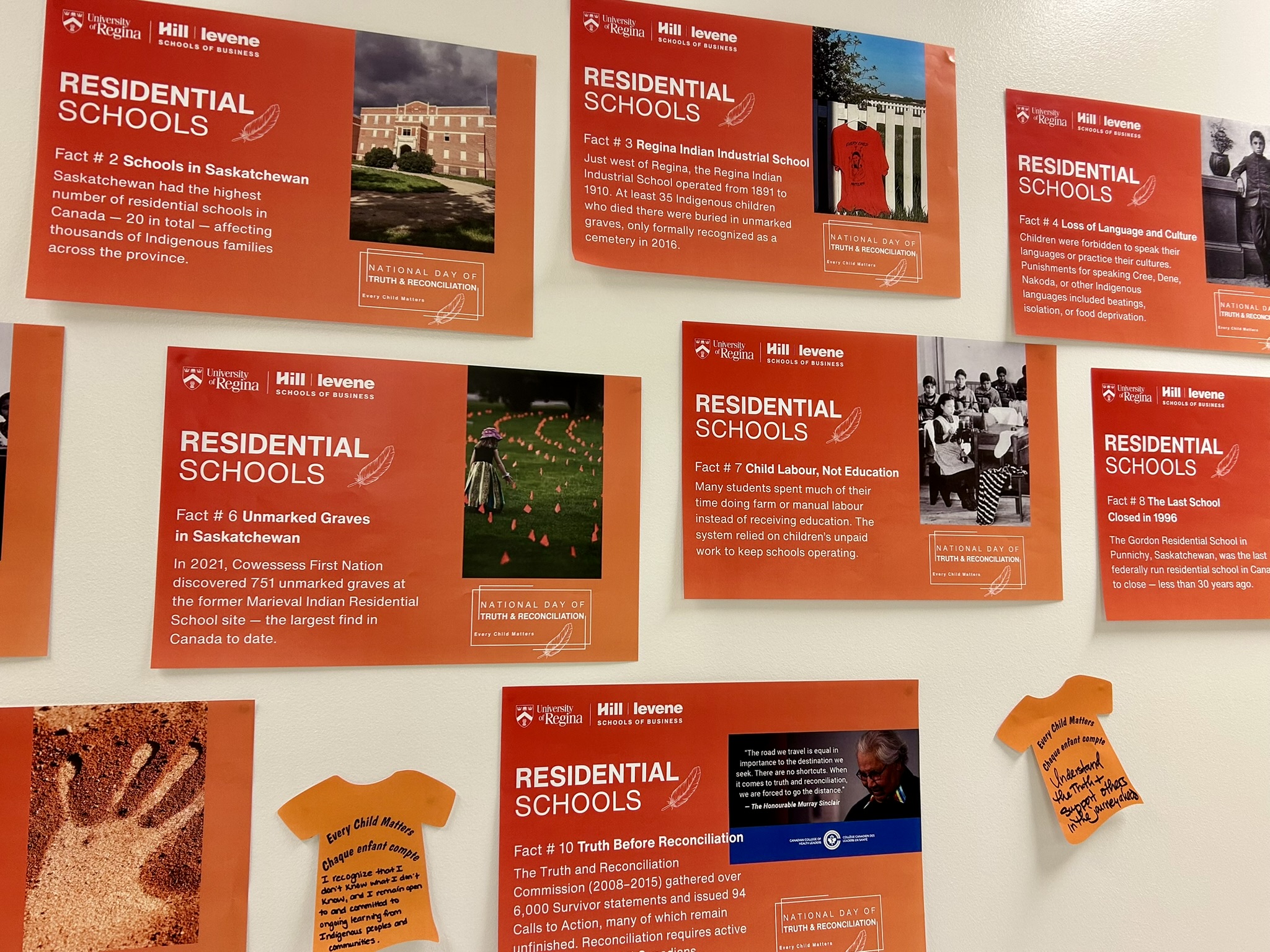 The Hill Levene School of Business reflection wall displays posters with facts about Truth and Reconciliation and residential schools, surrounded by orange t-shirt notes with personal calls to action.