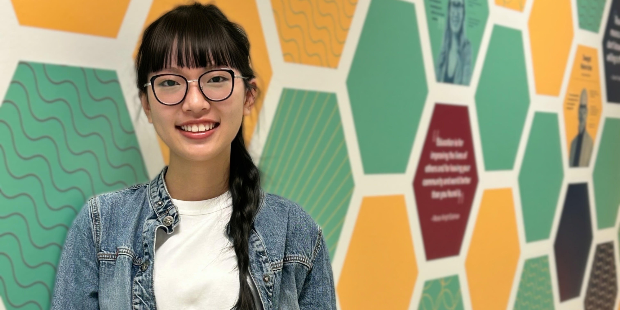 student smiling in front of colourful mural