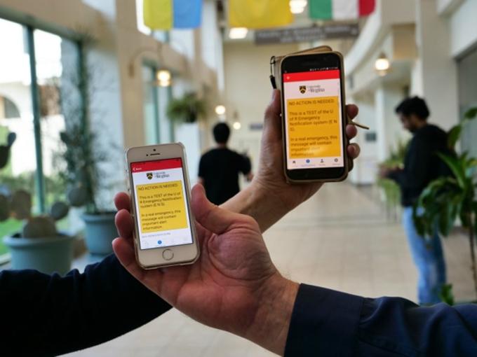 hands holding mobile phones showing messages from Alertus emergency app
