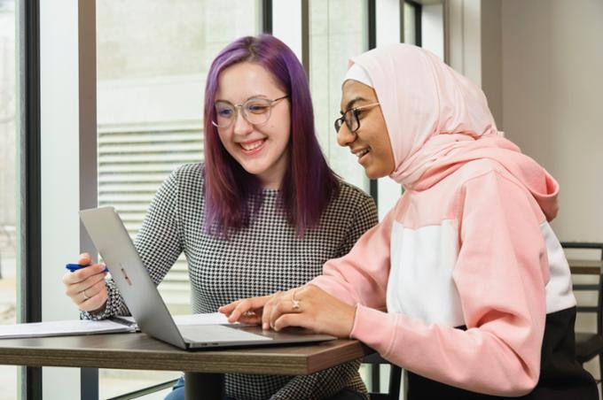 Two students studying and looking at laptop