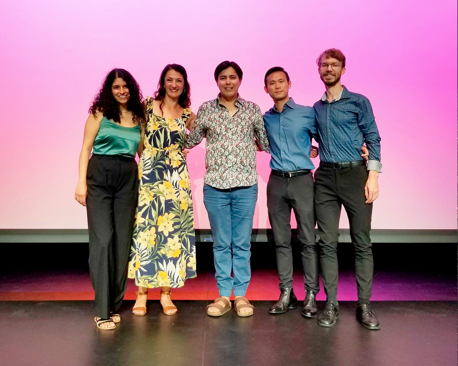 Five people posing for a photo on a stage