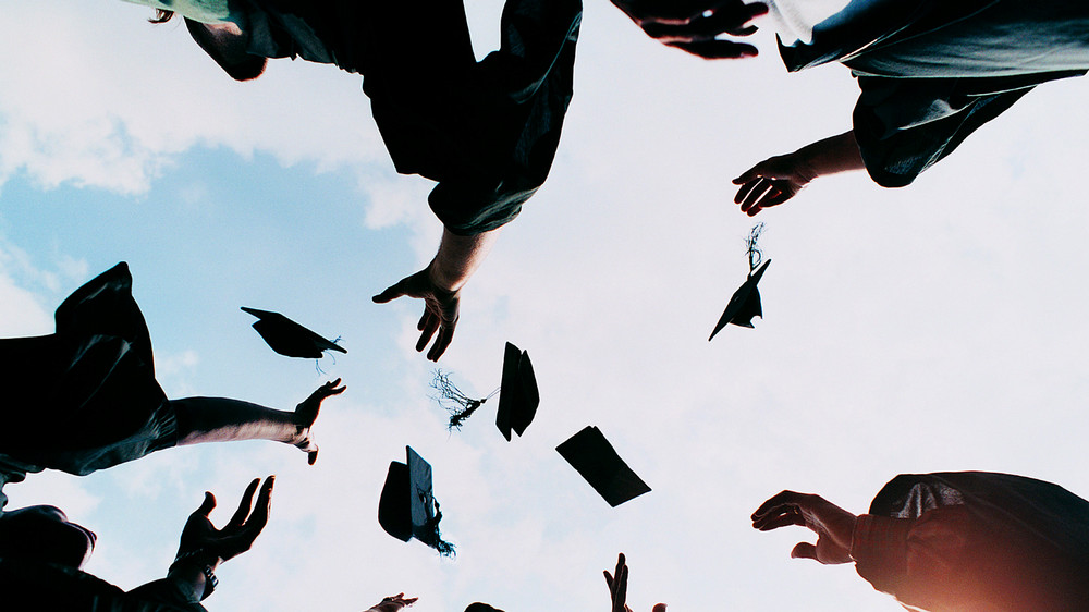 Hands throwing hats at a graduation ceremony