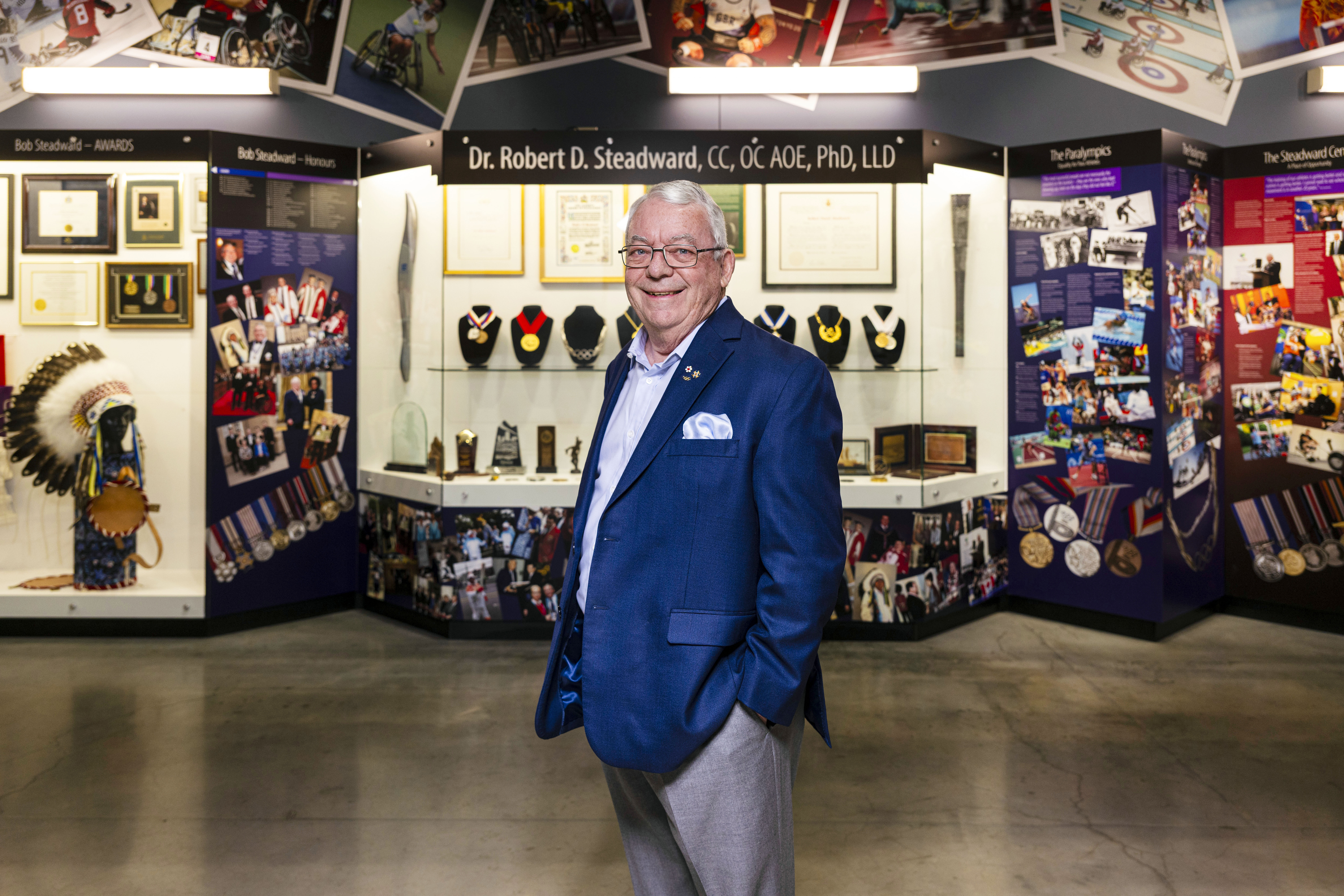 Bob is smiling in front of a display dedicated to his achievements