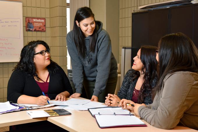 Four students sitting around a desk talking.