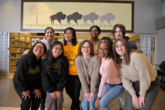 Student sitting on floor in library with lots of books
