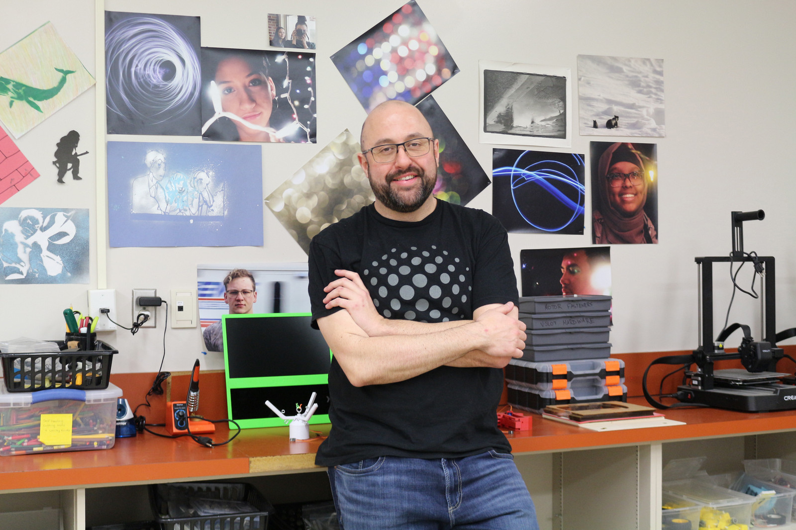 Cameron Wiest stands beside a row of 3D printers in the STEAM Academy classroom at F.W. Johnson Collegiate