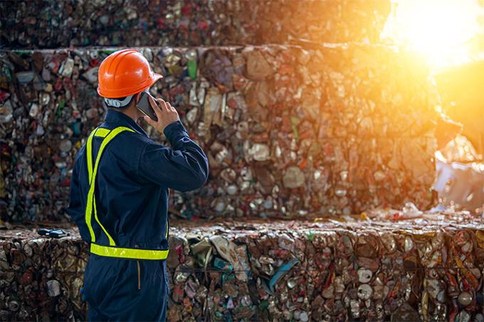 Person standing in front of a pile of trash on their phone