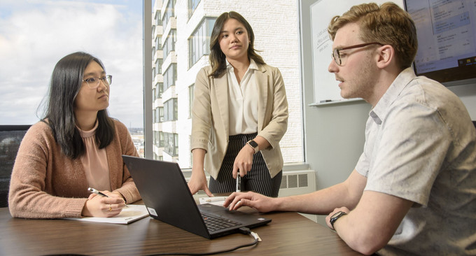 three people talking and looking at a laptop
