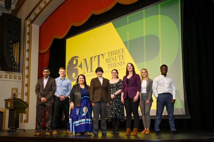 Several students on-stage at Three-Minute Thesis event.